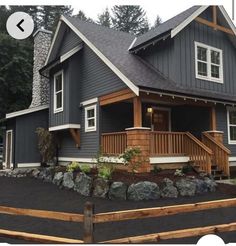 a gray house with white trim and wood accents on the front porch is featured in this video