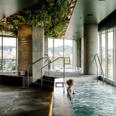 an indoor swimming pool with plants growing on the ceiling and stairs leading up to it