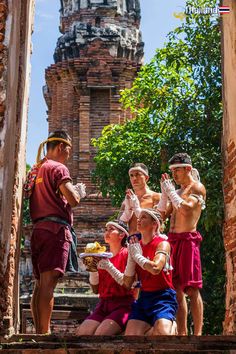 some people are standing in front of an old building and one is eating something out of a plate