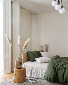 a bed with pillows and blankets in a bedroom next to a wooden table on the floor