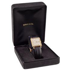 Tiffany & Co. 14k Yellow Gold Men's Hand-Winding Dress Watch w/ Original Box Movement #9255 Case #392906 14k Yellow Gold Square Case 26 mm Wide (27 mm w/ Crown) 27 mm Long Lug-to-Lug Distance = 37 mm Lug-to-Lug Width = 18 mm Thickness = 8 mm Champagne Art Deco Dial w/ Seconds Subdial Gold Tic Marks and Hands 23 mm Long x 23 mm Wide Black Leather Aftermarket Band w/ Gold-Plated Clasp Total Length = 8.25" Largest Wrist Fit = 7.75" Width at Case = 18 mm Width at Tip = 15 mm Total Mass = 29.3 grams Includes Original Tiffany & Co. Case Winding Dress, Art Deco Champagne, Champagne Art, Tiffany And Co, Dress Watch, Leather Band, Tiffany & Co., X 23, Leather Watch