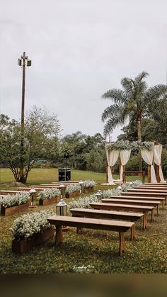 an outdoor ceremony with wooden benches and white drapes