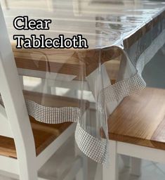 clear tablecloth on top of a wooden table with white chairs and wood flooring