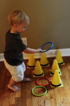 a little boy playing with some toys on the floor in front of cones and rings