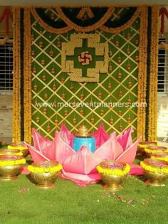 there is a flower arrangement in front of a wall with flowers on the grass and other decorations around it