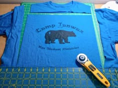 a t - shirt with a bear on it and a pair of scissors next to it