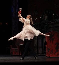 a woman in a white dress is performing on stage