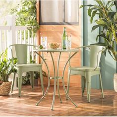 two chairs and a table on a wooden floor in front of a potted plant