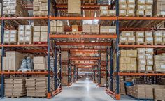 an industrial warehouse filled with lots of boxes and pallet racks full of items on the shelves