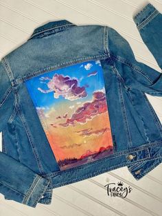 a denim jacket with an image of clouds painted on it