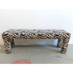 a zebra print bench sitting on top of a cement floor next to a white wall