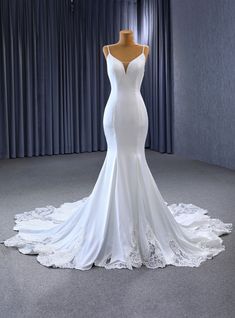 a white wedding dress on display in front of curtains