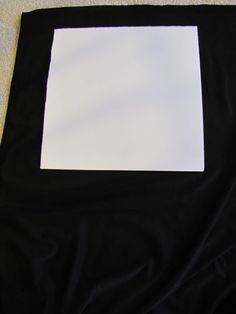 a square white piece of paper sitting on top of a black cloth covered flooring