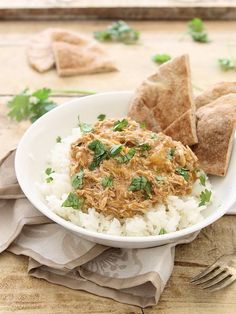 a white plate topped with rice and salsa next to tortilla chips on top of a wooden table