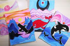 four paintings are shown on the table with one being an orca whale and another is dolphins