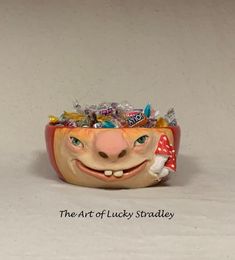 a ceramic head with candy in it on top of a white surface and the words, the art of lucky stradley