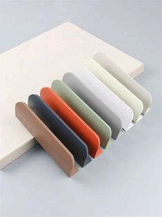 an assortment of different colored papers on a white surface with one folded in the middle