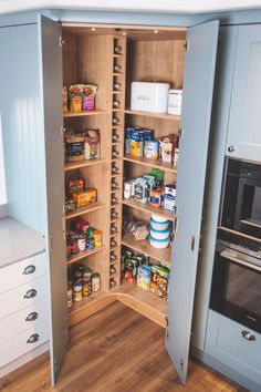 an open pantry door in a kitchen with wooden flooring and blue cupboards on both sides