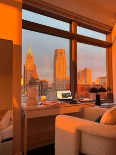 a laptop computer sitting on top of a desk in front of a window next to a chair