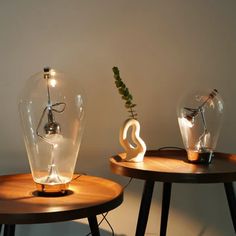 two glass vases sitting on top of wooden tables