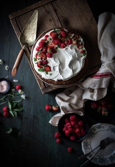 a cake with white frosting and strawberries on top, surrounded by other dessert items