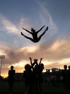 a person jumping in the air with their hands up while people watch from behind them