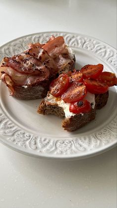 two pieces of bread with bacon and tomatoes on them