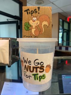 a plastic cup sitting on top of a table next to a sign that says tips