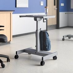 a hospital room with chairs and tables in the corner, one chair has a back pack on it