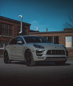 a white porsche cayen parked in front of a brick building