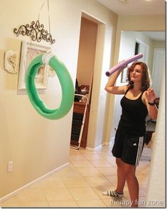 a woman holding a pink and green object in her hand while standing next to a doorway