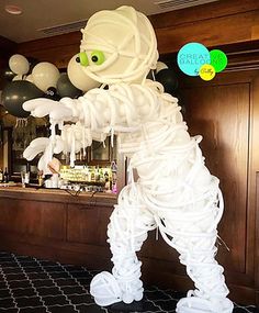 a skeleton is standing in front of a bar with balloons hanging from it's ceiling