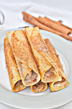 some food is on a white plate with cinnamon sticks next to it and a glass of wine