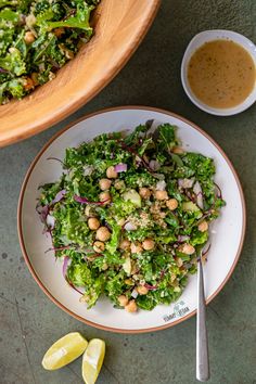 a salad with chickpeas and lettuce on a plate next to a bowl of dressing