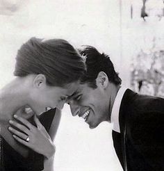 two people are laughing and touching each other's foreheads in black and white