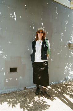 a woman standing in front of a wall with her hands on her hips and wearing sunglasses