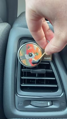 a person is holding a cd in the center console of a car with their finger on it