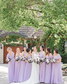 a group of women standing next to each other in front of a tree and building