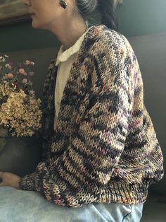 a woman sitting on a couch with flowers in her lap and looking off into the distance