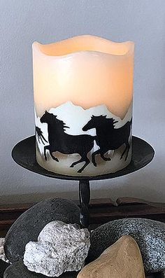 a lit candle sitting on top of a black plate next to rocks and a rock