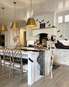 a kitchen decorated for halloween with skeletons and pumpkins on the counter, two hanging lights over the island