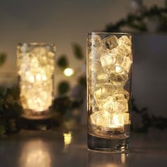 two glass vases with ice cubes in them sitting next to each other on a table