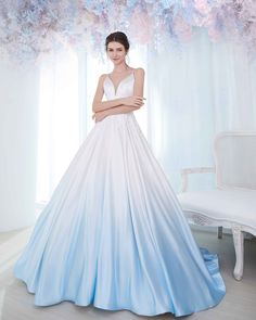 a woman in a blue and white wedding dress standing next to a floral tree with pink flowers