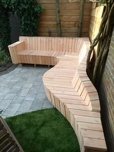 a wooden bench sitting on top of a green grass covered ground next to a tree