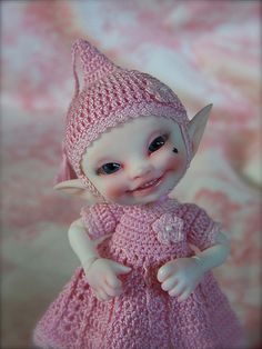 a small doll wearing a pink dress and hat