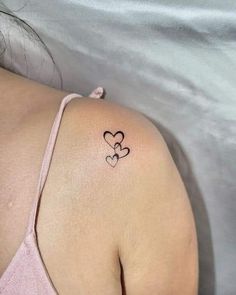 the back of a woman's shoulder with two hearts tattoo on her left arm