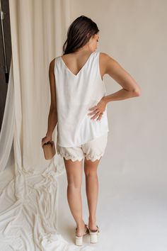 Introducing our Monroe Off White Satin Tank Top, a luxurious essential that epitomizes elegance and versatility. Crafted from sumptuously soft satin fabric in a timeless off-white hue, this tank top exudes sophistication with every wear. The graceful v-neckline adds a touch of allure, framing your décolletage with understated charm. Whether dressed up with statement jewelry for a night out or paired with casual denim for a relaxed daytime look, the Monroe Tank effortlessly transitions from day t Elegant V-neck Tank Top For Vacation, Elegant Sleeveless Camisole For Vacation, Chic White Cami Tank Top, White V-neck Camisole For Day Out, White Elegant Camisole Tank Top, Elegant White Camisole Tank Top, Cream Tank Top For Summer Daywear, Elegant Cream Camisole For Summer, Chic Cream Tank Top For Spring