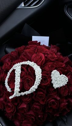 a bouquet of red roses with the letter d on it is in a car's dashboard