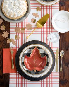 a table topped with plates and silverware next to a leaf shaped cookie on top of a plate