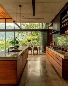 an open kitchen with wooden cabinets and counter tops, overlooking the forest outside through large windows